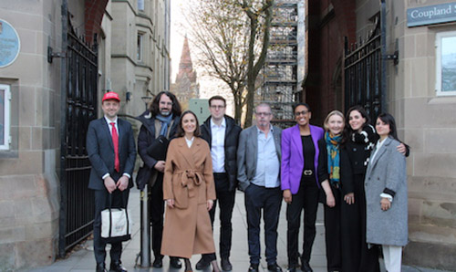 A group of Manchester International Law Centre staff standing together under a stone archway, posing for a photo.