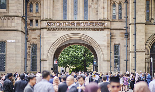 A crowd gathers at the University of Manchester's archway on Oxford Road.